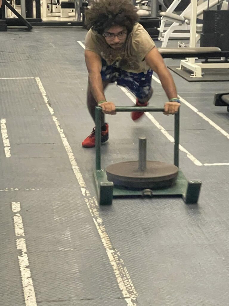 Strong Highschool student pushing weights, doing a sled push