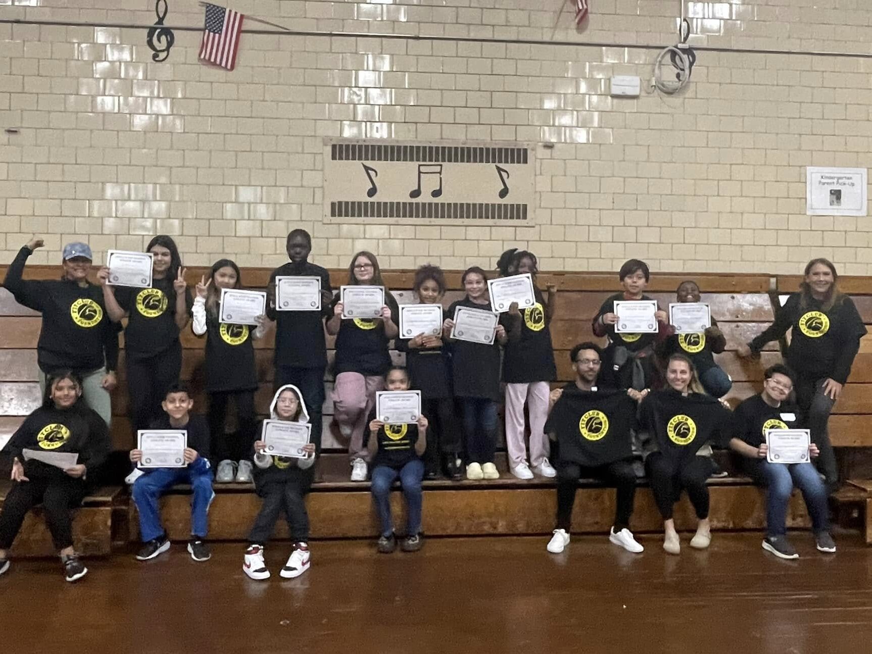 Group of middle school students wearing FITCLUB Foundation shirts and holding their certificates of completition.